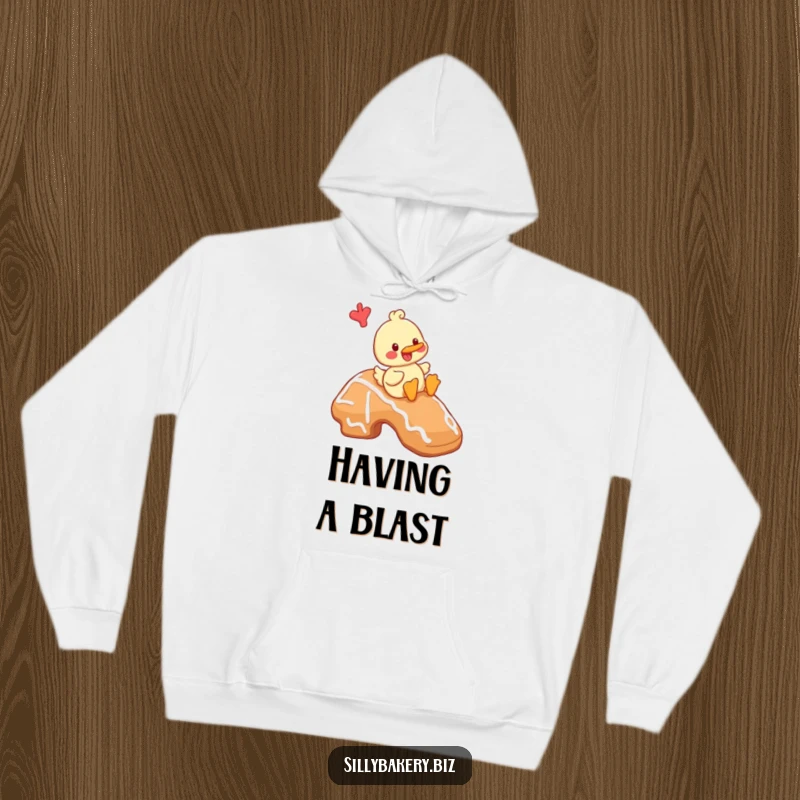 Funny duck hoodie showcasing a cheerful cartoon duck playfully sliding down a giant gingerbread cookie, a sweet and fun adventure.